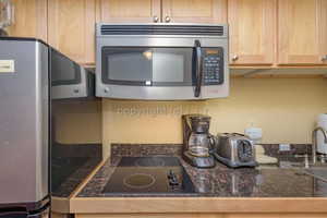 Kitchen with light brown cabinets, sink, and appliances with stainless steel finishes