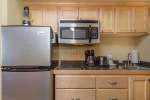 Kitchen featuring light brown cabinets, sink, and appliances with stainless steel finishes