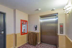 Interior space featuring a textured ceiling and elevator