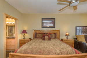 Bedroom featuring a textured ceiling, connected bathroom, and ceiling fan