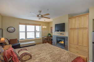 Bedroom with a tile fireplace and ceiling fan with notable chandelier