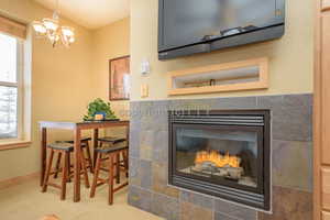 Details with carpet, an inviting chandelier, and a tiled fireplace