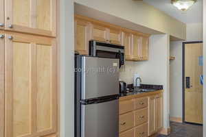 Kitchen featuring dark tile patterned flooring, sink, stainless steel appliances, and light brown cabinetry