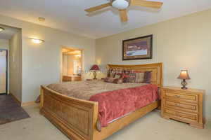 Bedroom with a textured ceiling, ceiling fan, and light carpet