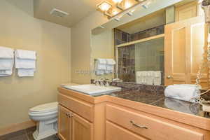 Bathroom with tile patterned flooring, vanity, toilet, and a shower with shower door