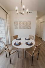 Picture is of model home. Dining space with wood-type flooring and a chandelier