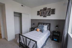 Picture is of model home. Bedroom featuring carpet and a closet