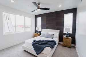 Picture is of model home. Bedroom featuring light colored carpet and ceiling fan