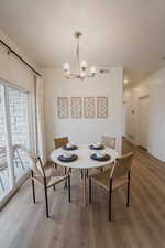 Picture is of model home. Dining area featuring hardwood / wood-style floors, breakfast area, and a chandelier