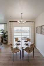 Picture is of model home. Dining area featuring wood-type flooring, a wealth of natural light, and an inviting chandelier