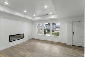 Unfurnished living room with a raised ceiling and light wood-type flooring