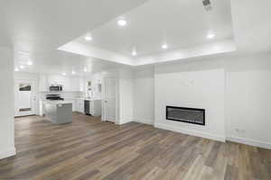 Unfurnished living room featuring hardwood / wood-style flooring, sink, and a tray ceiling