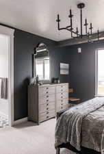 Bedroom featuring a textured ceiling, light carpet, and a chandelier