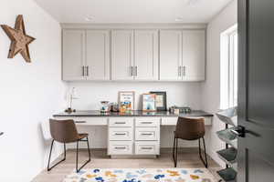 Home office with light hardwood / wood-style flooring and built in desk