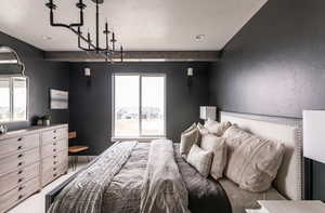 Bedroom with multiple windows, beamed ceiling, a textured ceiling, and a notable chandelier