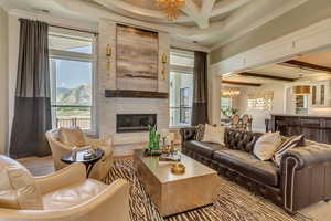 Living room featuring beamed ceiling, plenty of natural light, and a notable chandelier