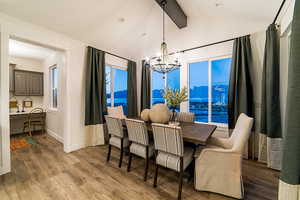 Dining area with an inviting chandelier, dark hardwood / wood-style floors, built in desk, and lofted ceiling with beams