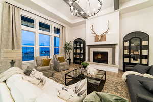 Living room featuring wood-type flooring, a fireplace, a chandelier, and a tray ceiling