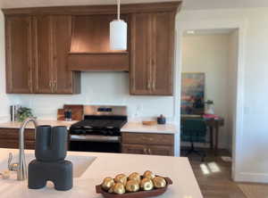 Kitchen featuring gas range, sink, hanging light fixtures, hardwood / wood-style floors, and extractor fan