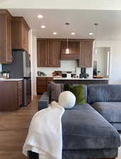 Kitchen with a kitchen bar, decorative light fixtures, stainless steel refrigerator, and dark wood-type flooring