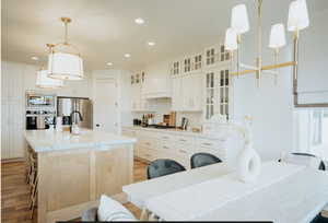 Kitchen with pendant lighting, recessed lighting, a center island with sink, premium range hood, and tasteful backsplash