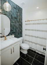 Bathroom featuring vanity, a shower with curtain, dark tile patterned flooring, and recessed lighting