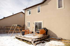 Snow covered back of property with a deck