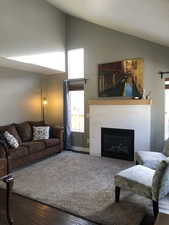 Living room with a tiled fireplace, hardwood / wood-style floors, and high vaulted ceiling