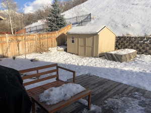 Snow covered deck featuring a storage shed