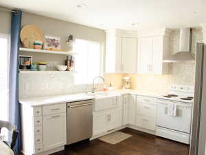 Kitchen featuring dark wood-type flooring, white cabinets, white electric stove, stainless steel dishwasher, and wall chimney exhaust hood