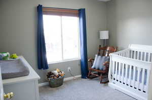 Carpeted bedroom featuring a nursery area