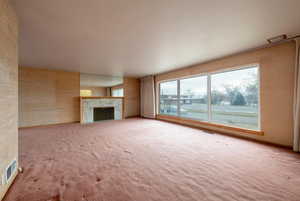 Living room with fireplace and hardwood floors under carpet