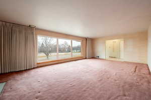 Living room with beautiful picture window looking out to the west and SLC sunsets, hardwood floors under carpet