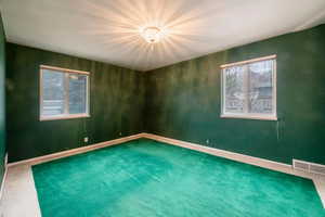 Second bedroom on main floor with two windows and hardwood floors under carpet