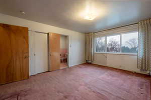 Primary bedroom with bathroom, and hardwood floor under carpet