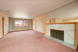 Living room with fireplace looking into dining room and hardwood floors under carpet