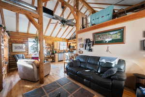 Living room featuring hardwood / wood-style flooring, ceiling fan, beamed ceiling, and high vaulted ceiling