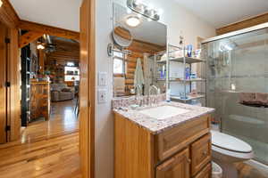 Bathroom featuring hardwood / wood-style floors, vanity, toilet, and an enclosed shower