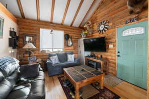 Living room with beamed ceiling, wood-type flooring, and log walls