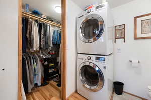 Clothes washing area featuring stacked washer and dryer and light wood-type flooring