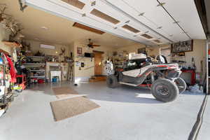 Garage with a workshop area, an AC wall unit, and ceiling fan