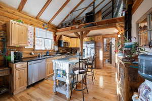 Kitchen with a center island, beam ceiling, light brown cabinetry, appliances with stainless steel finishes, and light hardwood / wood-style floors