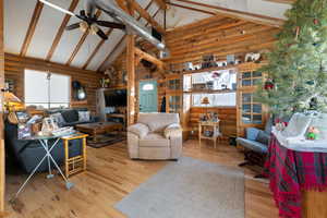 Living room with beam ceiling, ceiling fan, high vaulted ceiling, and wood-type flooring