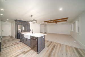 Kitchen featuring stainless steel refrigerator, dark brown cabinetry, dishwasher, and light hardwood / wood-style flooring