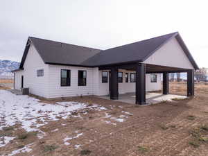 Snow covered rear of property with cooling unit