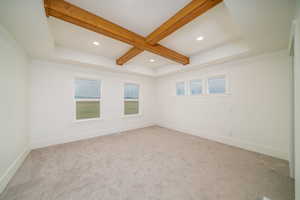 Carpeted spare room with beamed ceiling