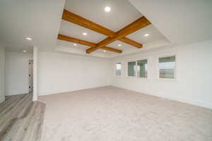 Empty room with beamed ceiling and light wood-type flooring