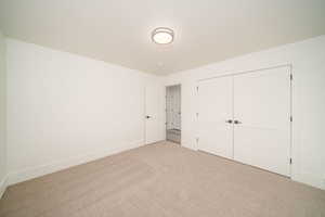 Unfurnished bedroom with light carpet and a closet