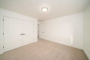 Unfurnished bedroom with light carpet and a closet