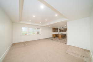 Unfurnished living room with light carpet and a raised ceiling